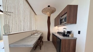 A compact kitchen with a central island, wooden cabinets, and a modern light fixture. - PH de 2 rec, gim, cine y jacuzzi privado en Tulum (Tulum)