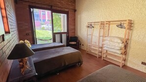 A room with two beds, a wooden bench, a hanging clothes rack, and a view of the outside. - Casa na Serra Para 15 Pessoas Bento Gon Alves (Bento Gonçalves)
