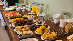 A buffet with various food items and beverages. - Pousada Karandá (Serra Negra)
