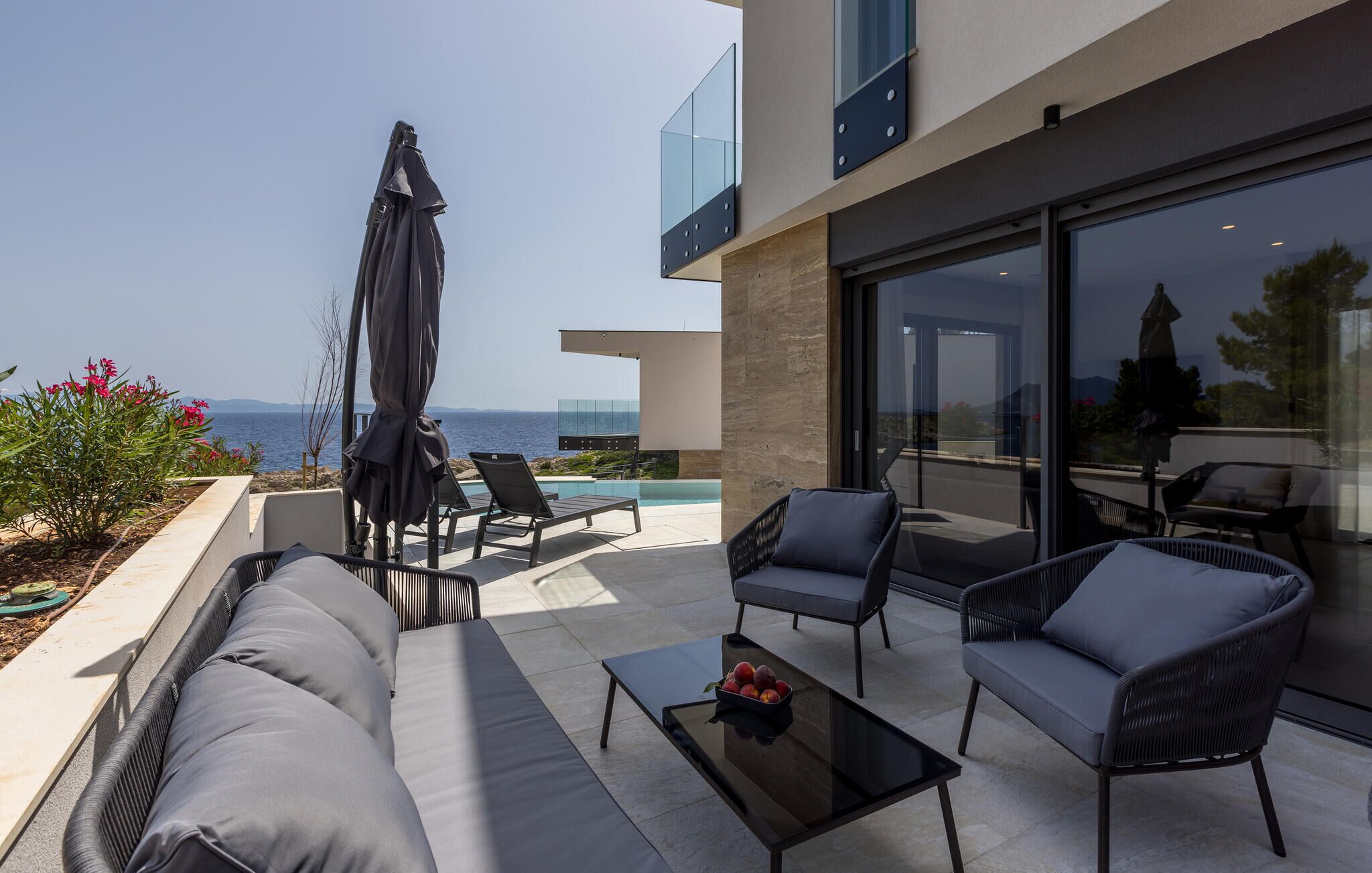 Un espace extérieur moderne avec des sièges et une piscine, offrant une vue sur la mer.