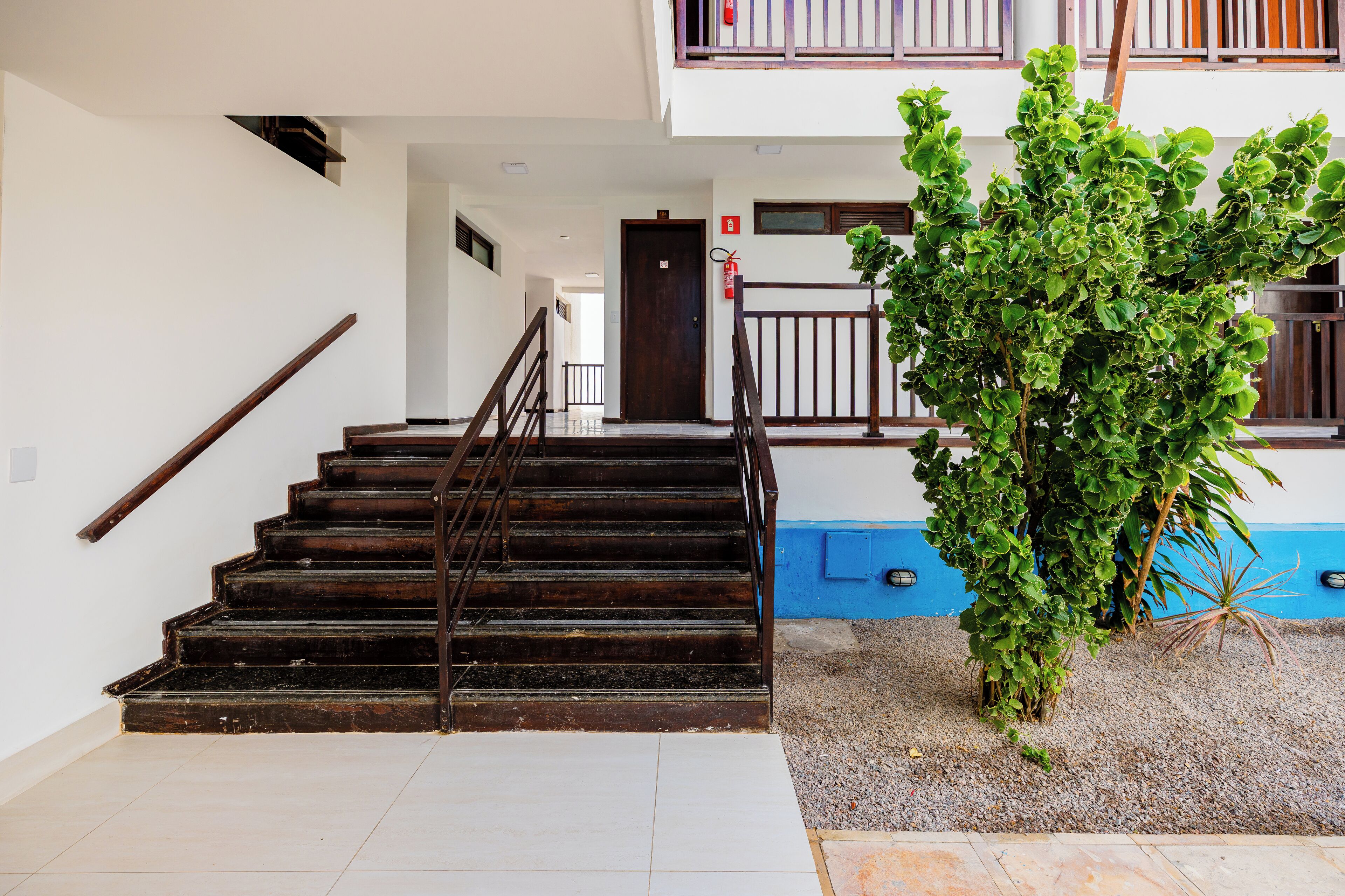 Una escalera de madera con barandas de metal que lleva a una puerta.