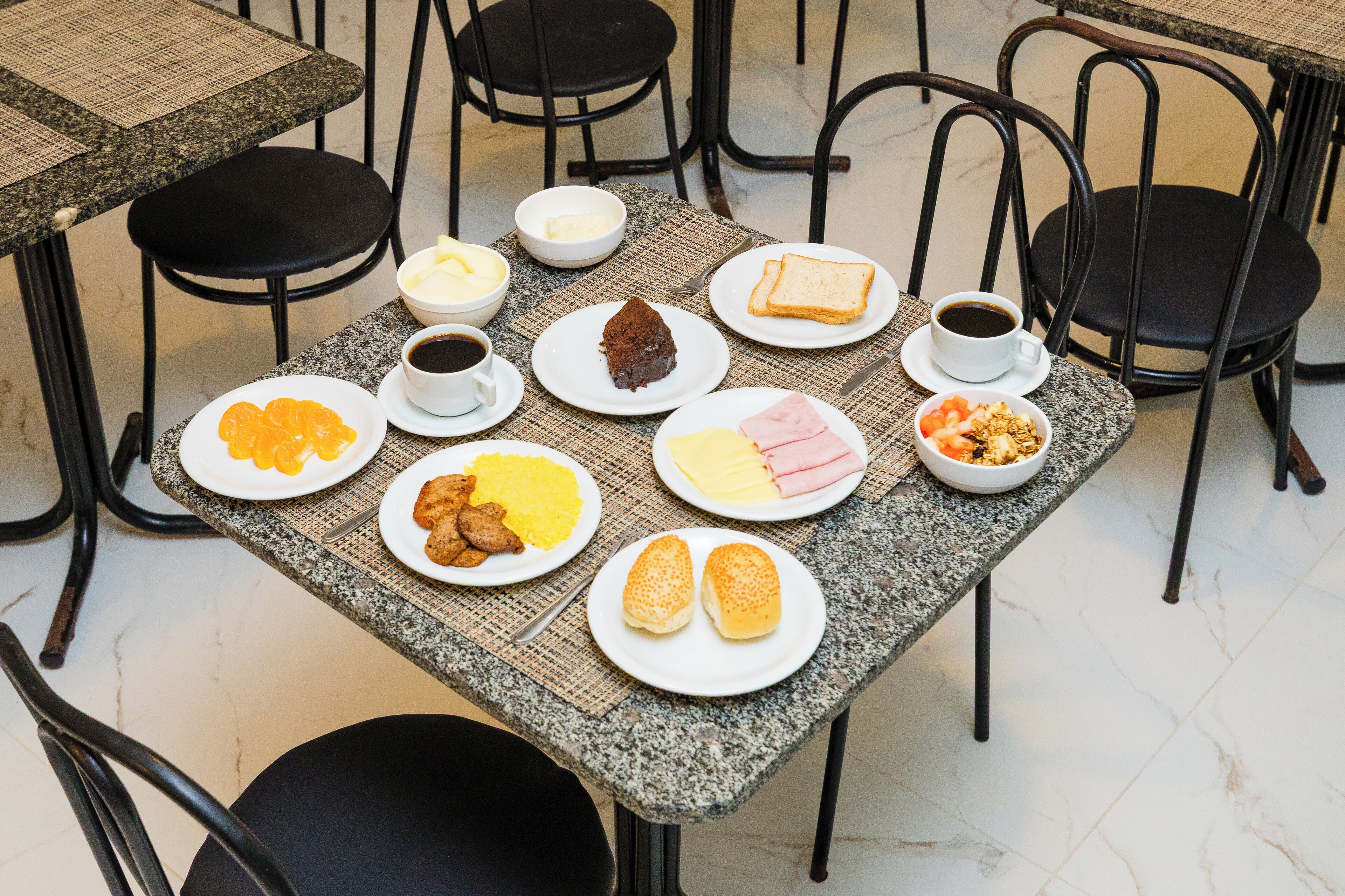 Una mesa de comedor con diversos alimentos para el desayuno, como tostadas, huevos y café.