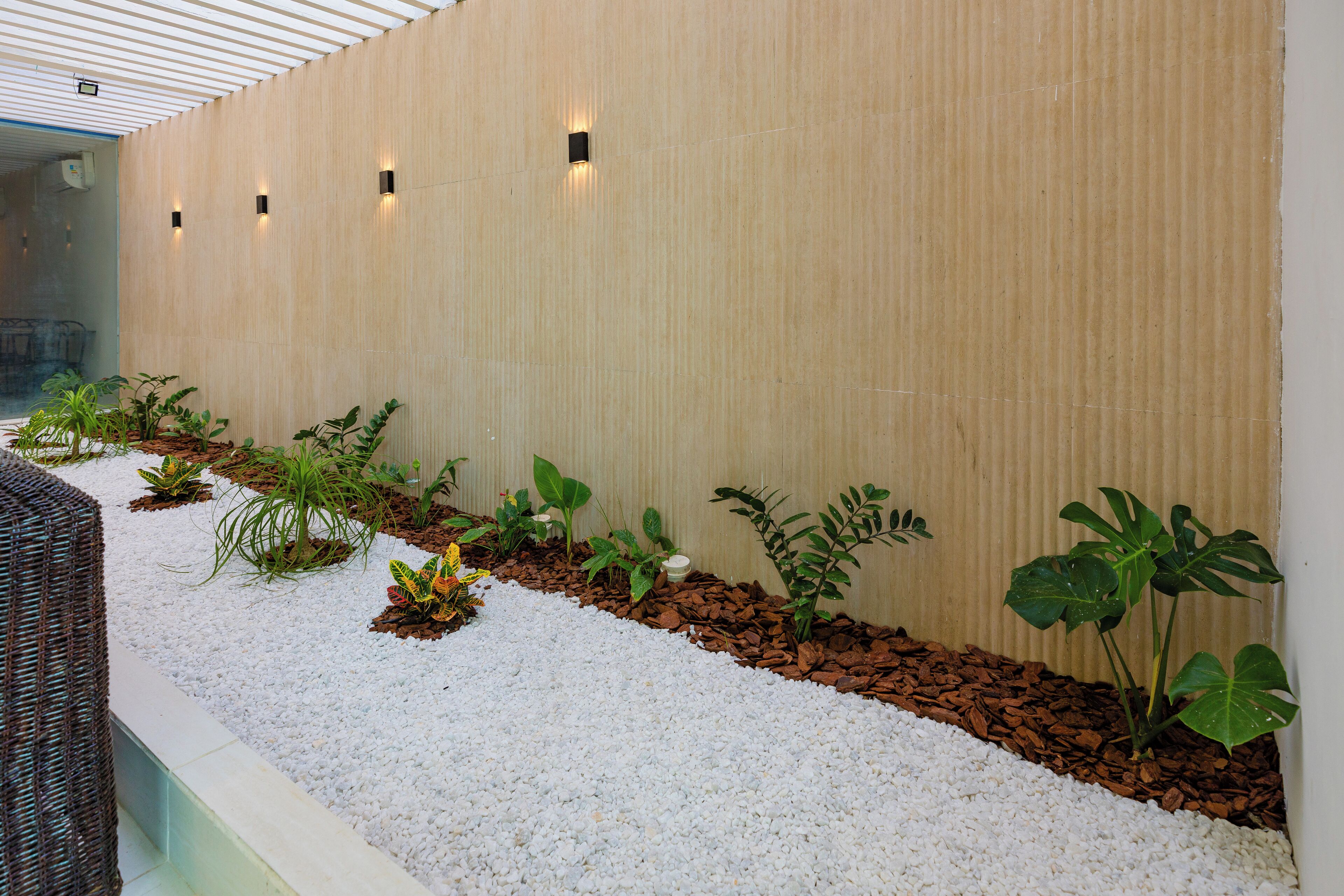 A modern indoor garden with a variety of plants and a pebble pathway.