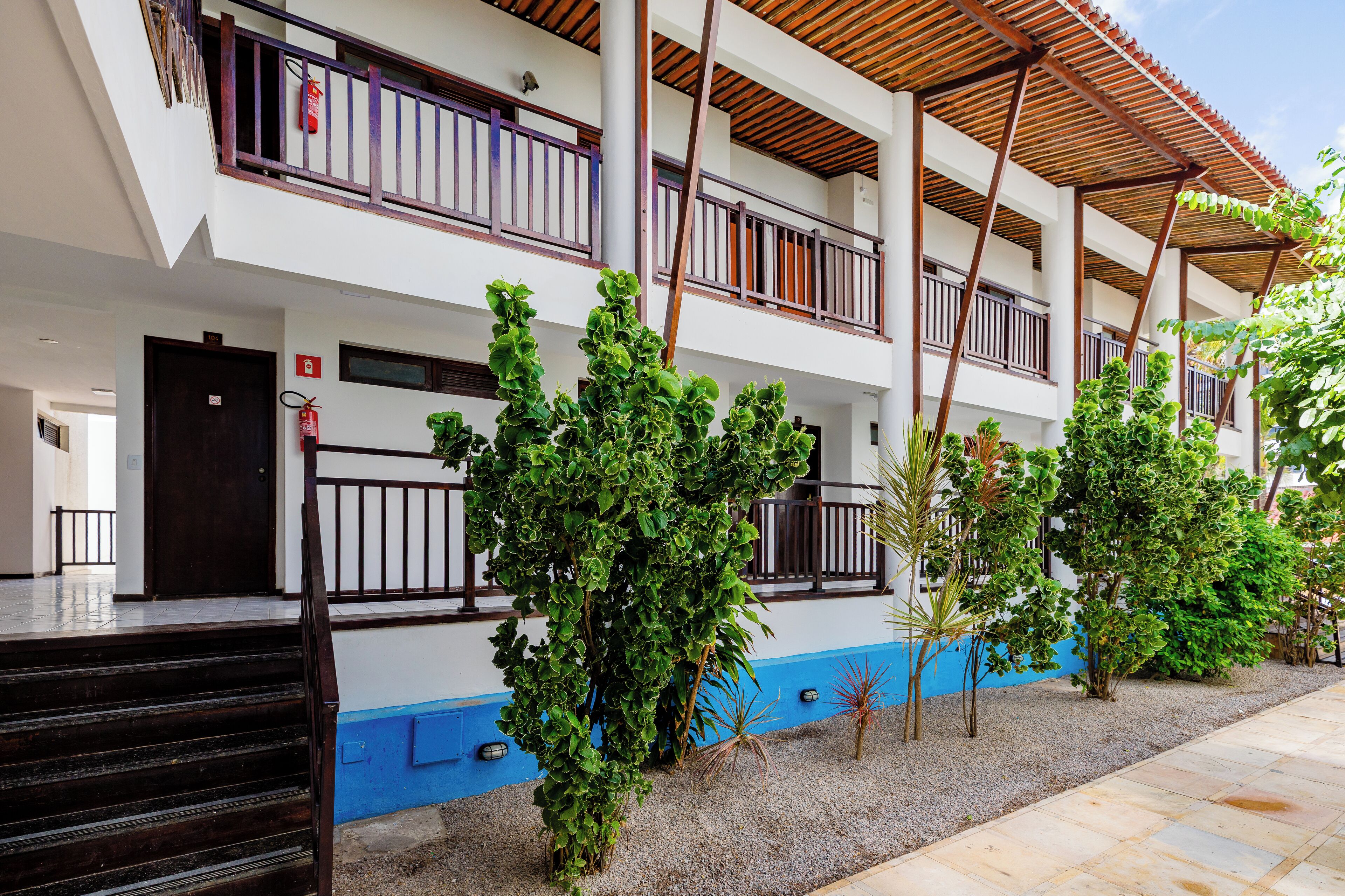Um edifício de vários andares com fachada azul e branca, escadas externas e uma galeria coberta com corrimãos.