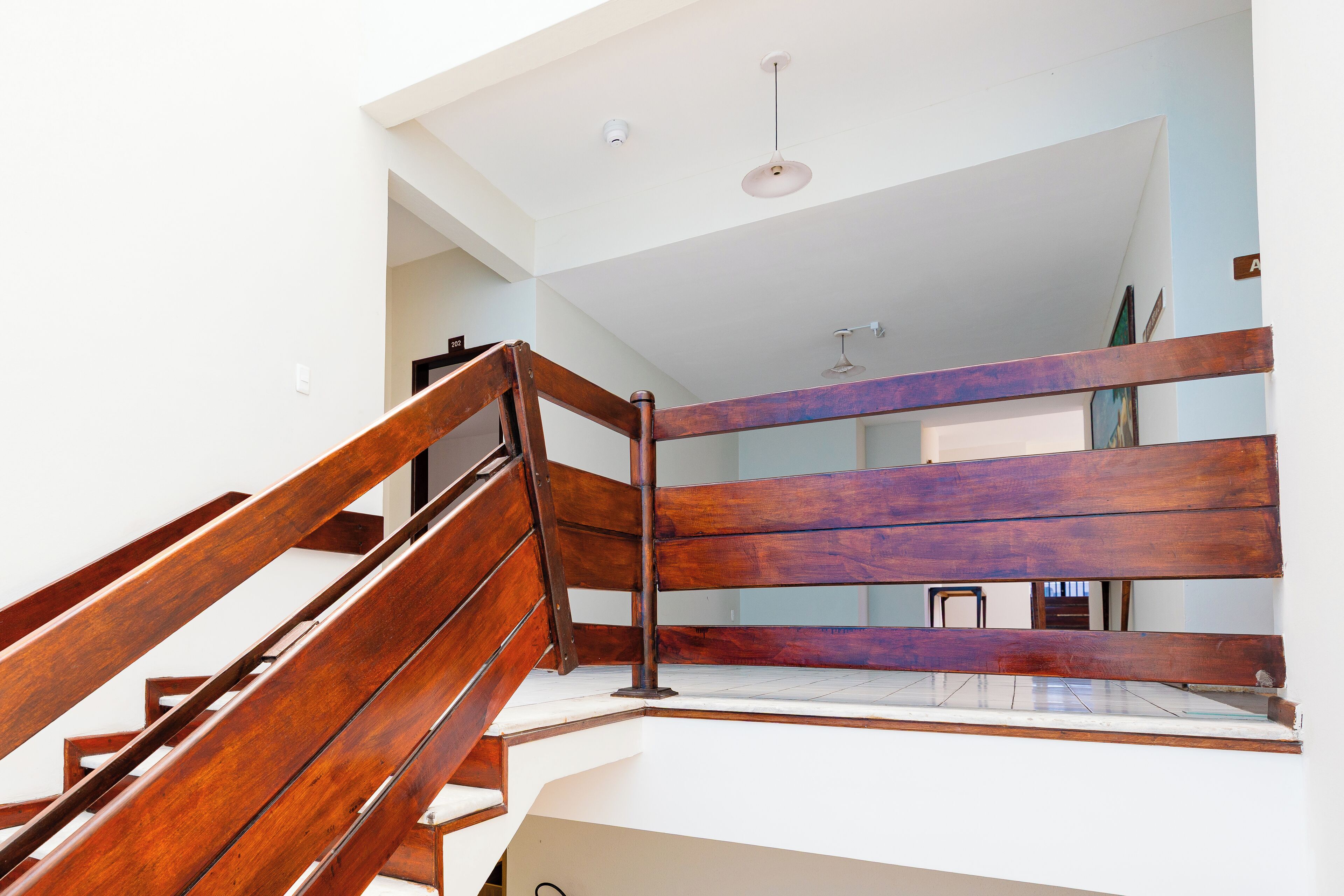 A wooden staircase with a metal handrail leading to a landing.