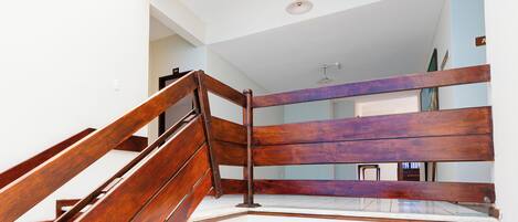 A wooden staircase with a metal handrail leading to a landing.