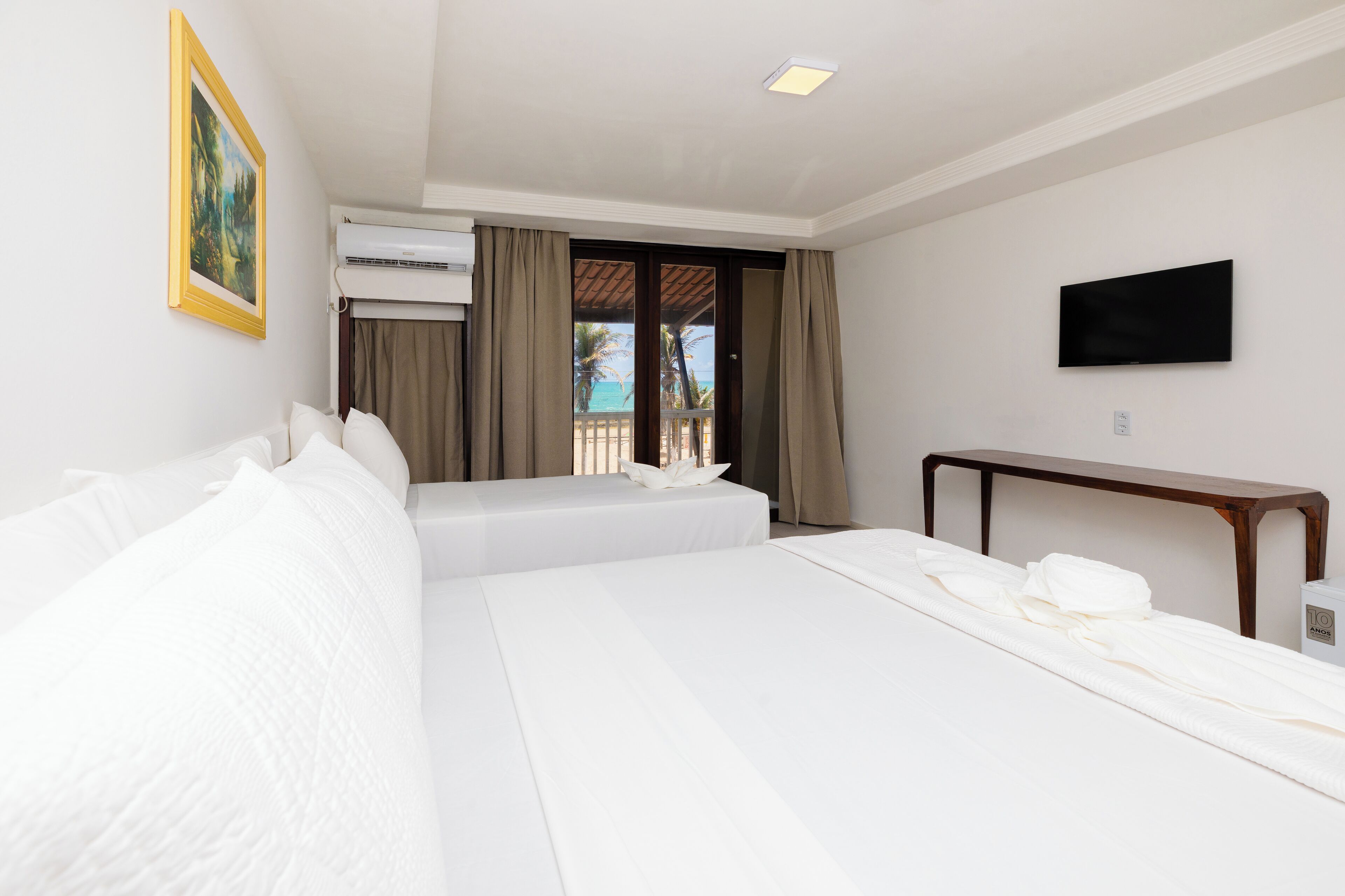 Une chambre d’hôtel dotée d’un grand lit, d’un téléviseur à écran plat, de la climatisation et offrant une vue sur l’océan grâce à une porte coulissante.