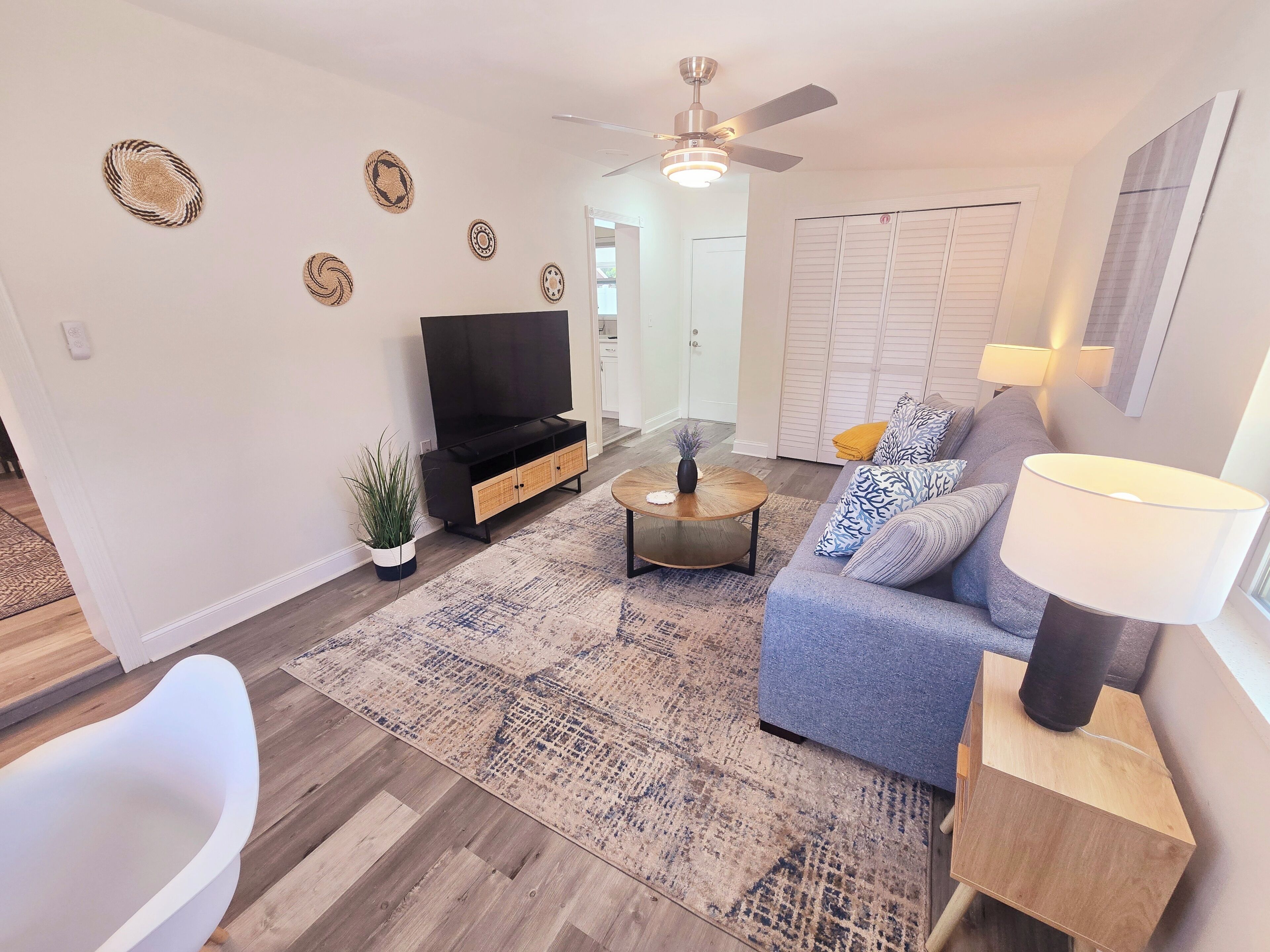 A living room with a sofa, coffee table, TV, and a ceiling fan.