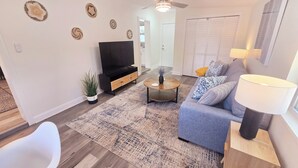 Ein Wohnzimmer mit Sofa, Couchtisch, Fernseher und Deckenventilator.