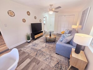 Ein Wohnzimmer mit Sofa, Couchtisch, Fernseher und Deckenventilator.