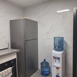 Uma cozinha com geladeira de aço inoxidável, um dispensador de água e um jarro grande.