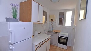 A compact kitchen with a white refrigerator, a built-in oven, and a sink. - Antunovic / Antunovic 1 (Veli Lošinj)