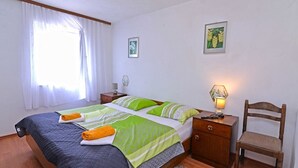 A neatly arranged bedroom with a bed, bedside tables, a chair, and a lamp. - Antunovic / Antunovic 1 (Veli Lošinj)