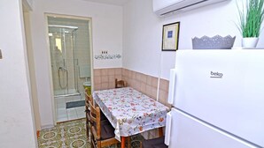 A compact kitchen with a dining table, a refrigerator, and a shower area. - Antunovic / Antunovic 1 (Veli Lošinj)