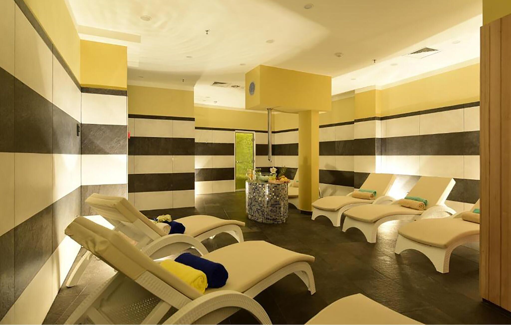 A spa room with striped walls, multiple sun loungers, and a central decorative column.