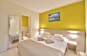 A hotel room with a bed, bedside tables, a painting, and a bathroom visible through an open door. - Lovely apartment in Biograd with sauna (Biograd)