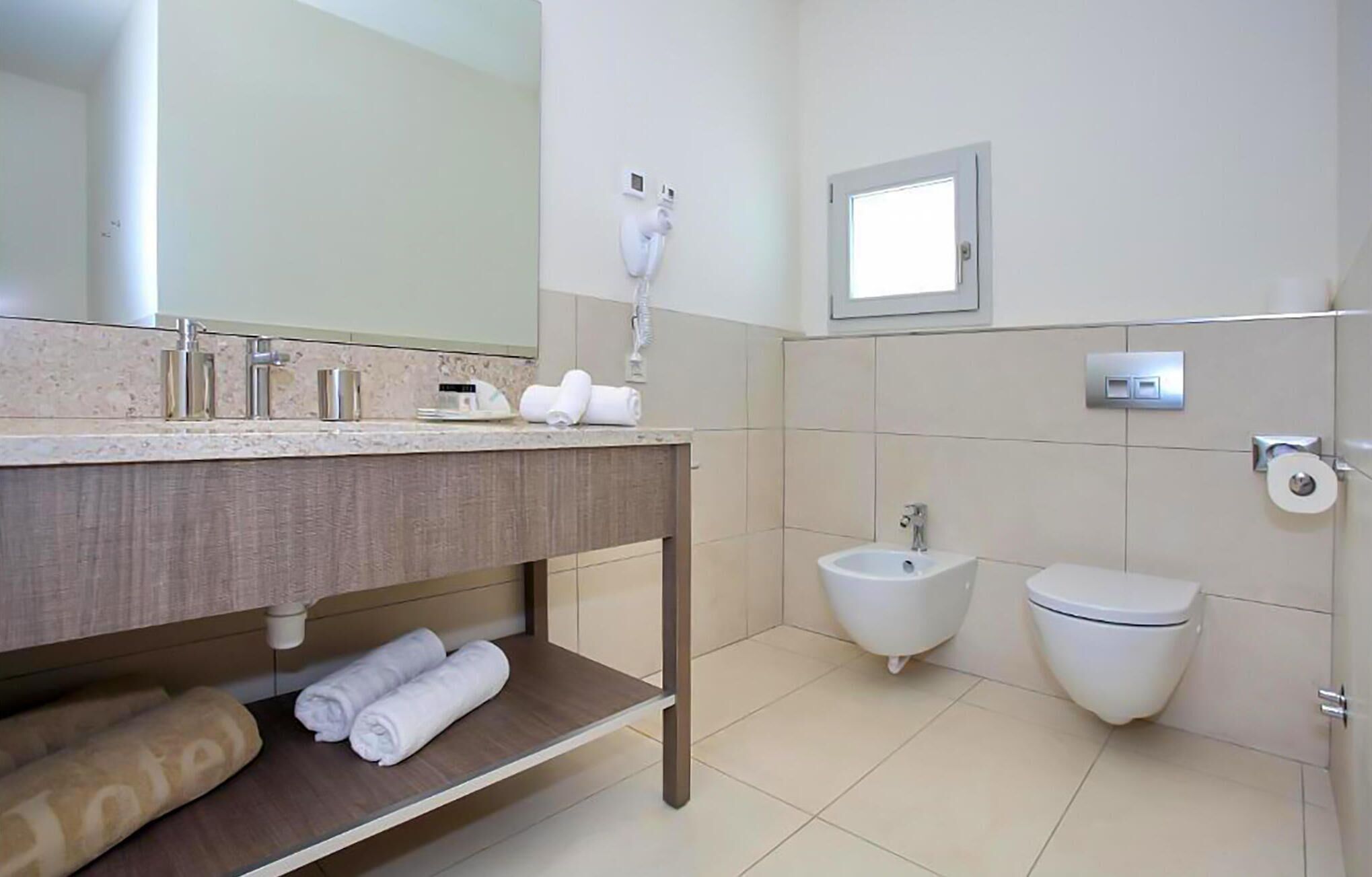 Ein modernes Badezimmer mit Waschtisch, Bidet, Toilette und Handtuchhalter.
