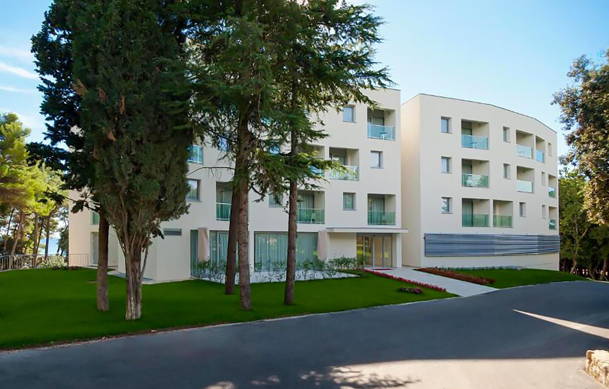 Ein modernes, mehrstöckiges Gebäude mit geschwungener Fassade, großen Fenstern und einem gepflegten Rasen.