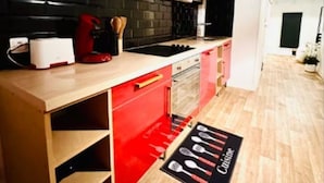 A modern kitchen with red cabinets, a black backsplash, and a wooden countertop.