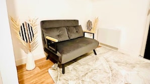 A modern living room with a dark grey sofa, a patterned rug, wooden flooring, and decorative vases.