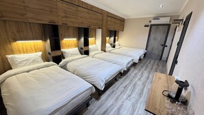 Ett hotellrum med fyra sängar, trägavlar och en minibar.