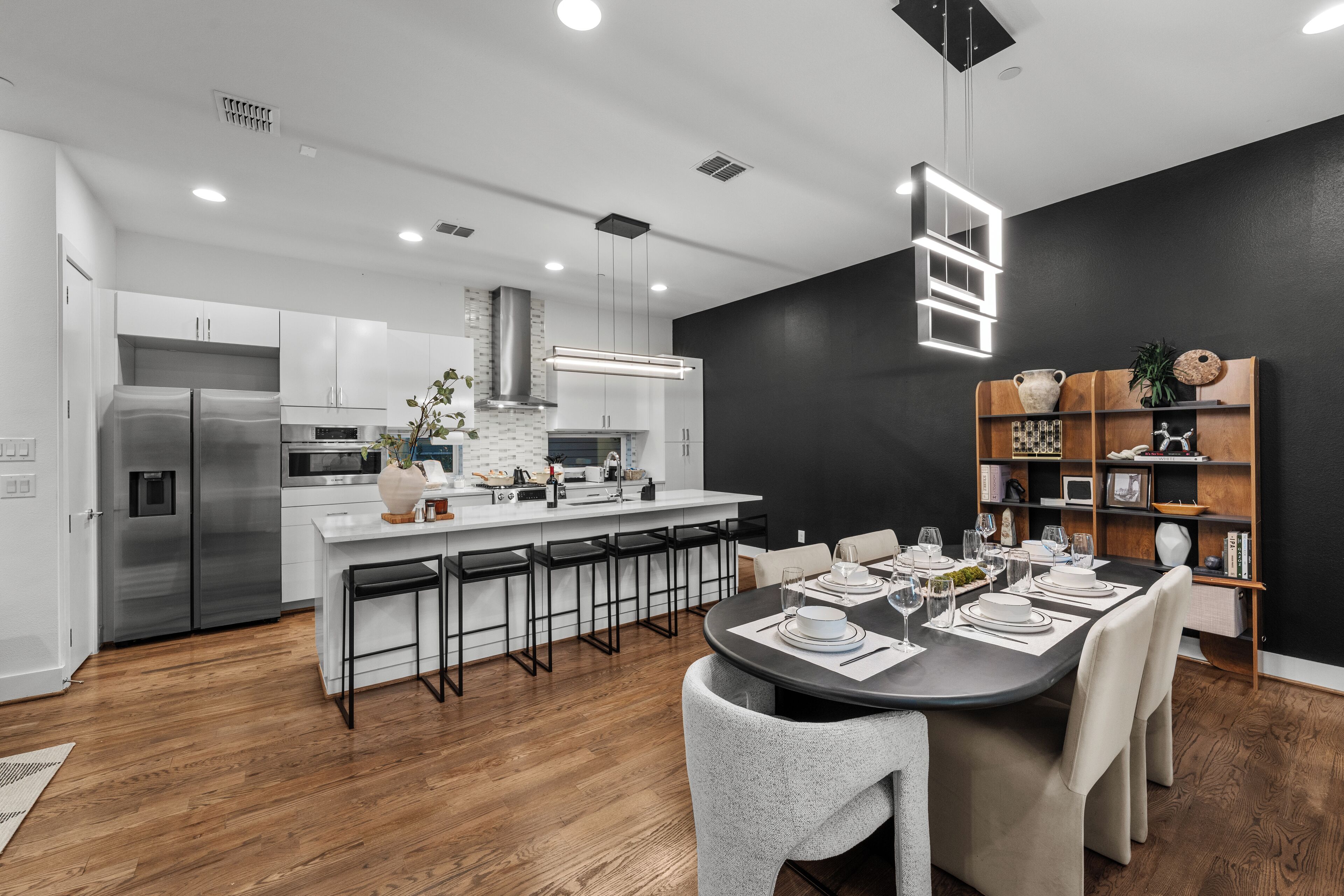 Una cocina moderna con armarios blancos, electrodomésticos de acero inoxidable y una isla central con taburetes de bar.