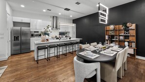 Cozinha moderna com armários brancos, eletrodomésticos de aço inoxidável e uma ilha central com banquetas.