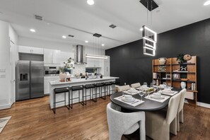 A modern kitchen with white cabinets, stainless steel appliances, and a central island with bar stools. - Luxury 3BR Dallas Bishop Arts! Rooftop + Skyline + MiniGolf + Firepit + Garage (Dallas)