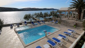 Ett poolområde med blå solstolar och utsikt över havet.