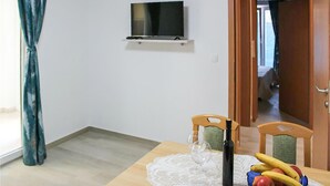 En matplats med ett bord dukat för två personer, en tv som är monterad på väggen och en dörr som leder till ett annat rum.
