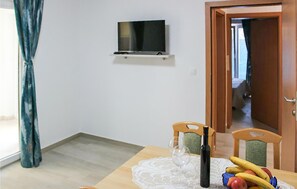 Ein Essbereich mit Tisch für zwei Personen, einem an der Wand montierten Fernseher und einer Tür zu einem anderen Raum.