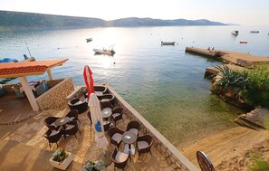 A terrace with outdoor seating overlooking a calm body of water, boats, and distant hills. - Amazing apartment in Stara Novalja with outdoor swimming pool (Stara Novalja)