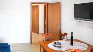 Een eetgedeelte met een houten tafel, stoelen en een aan de muur bevestigde televisie.