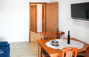 Ein Essbereich mit Holztisch, Stühlen und einem an der Wand befestigten Fernseher.