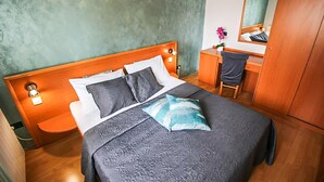 A neatly made bed with a patterned bedspread and pillows, a wooden headboard, a bedside table with a lamp, and a small desk with a chair. - Gorgeous apartment in Stara Novalja with outdoor swimming pool (Stara Novalja)