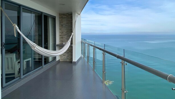 Un balcon avec un hamac, des portes vitrées et une vue sur l’océan.