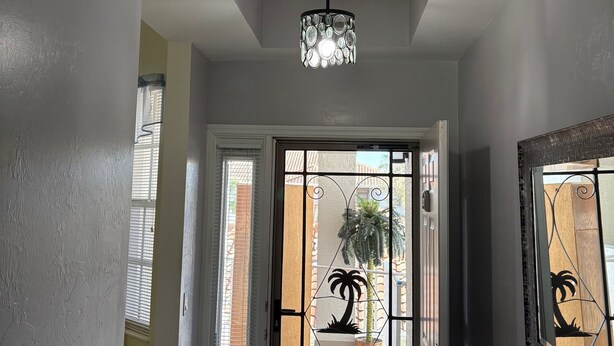 A hallway with a ceiling light fixture, a door with a decorative glass panel, and a view of the outside through the door. - Legends Country Club Social 2/2 Condo Overlooking Hole #1, Close to Country Club (Fort Myers)