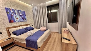 Ein modernes Schlafzimmer mit einem hölzernen Bett, einem Fernseher, einem Nachttisch und einem Gemälde an der Wand.