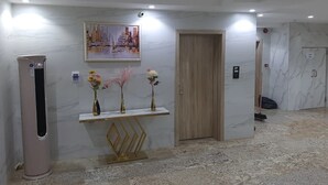 Egy modern előtér márványburkolattal, fa ajtóval és a falra akasztott képpel.