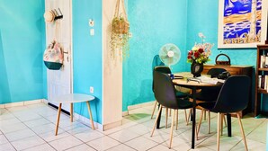 A dining area with a round table, chairs, a fan, and a bookshelf. - Anemeli 2 bedroom Apartment, Stoupa, 50m to beach. Stunning Sea & Mountain views (Stoupa)