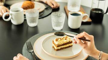 Una mesa de comedor con un plato de pastel, una taza de café y un vaso de agua.