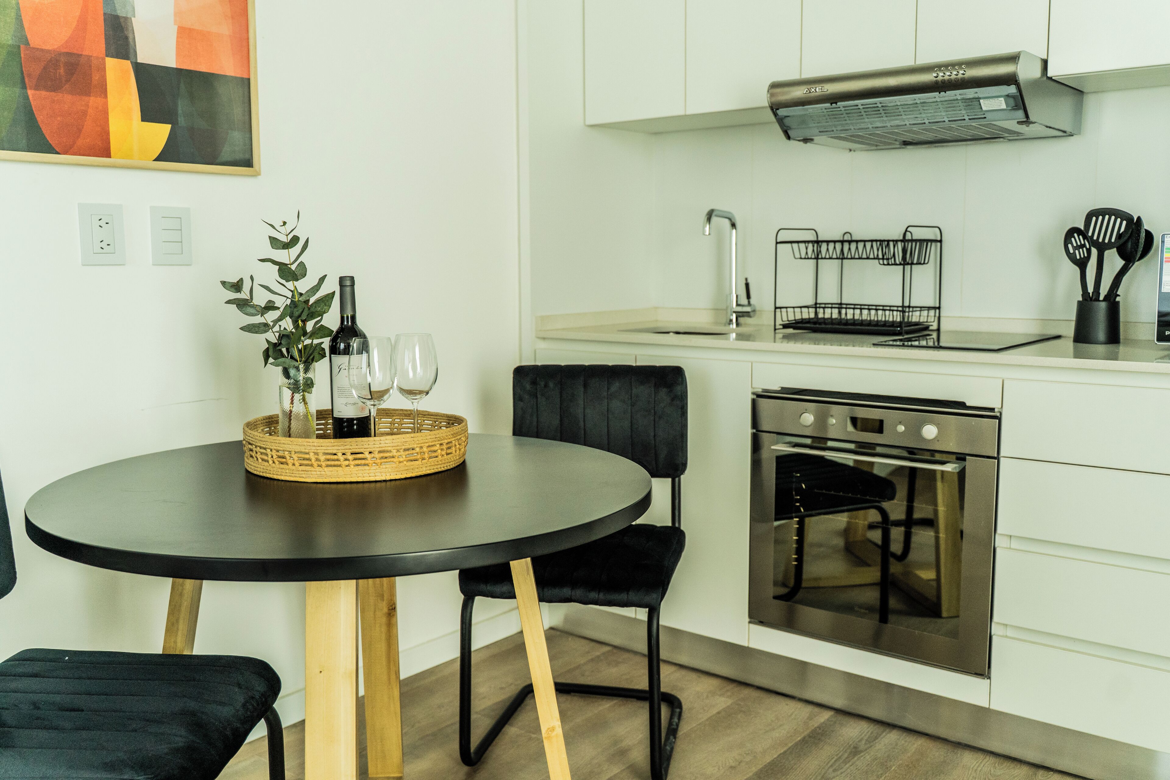 Une cuisine moderne avec une table ronde, des chaises noires, une cuisinière et un évier.