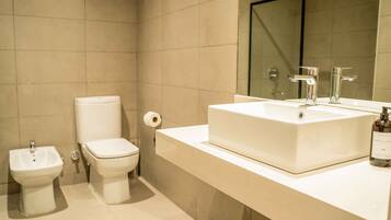 A bathroom with a bidet, toilet, and a large sink with a mirror above it.