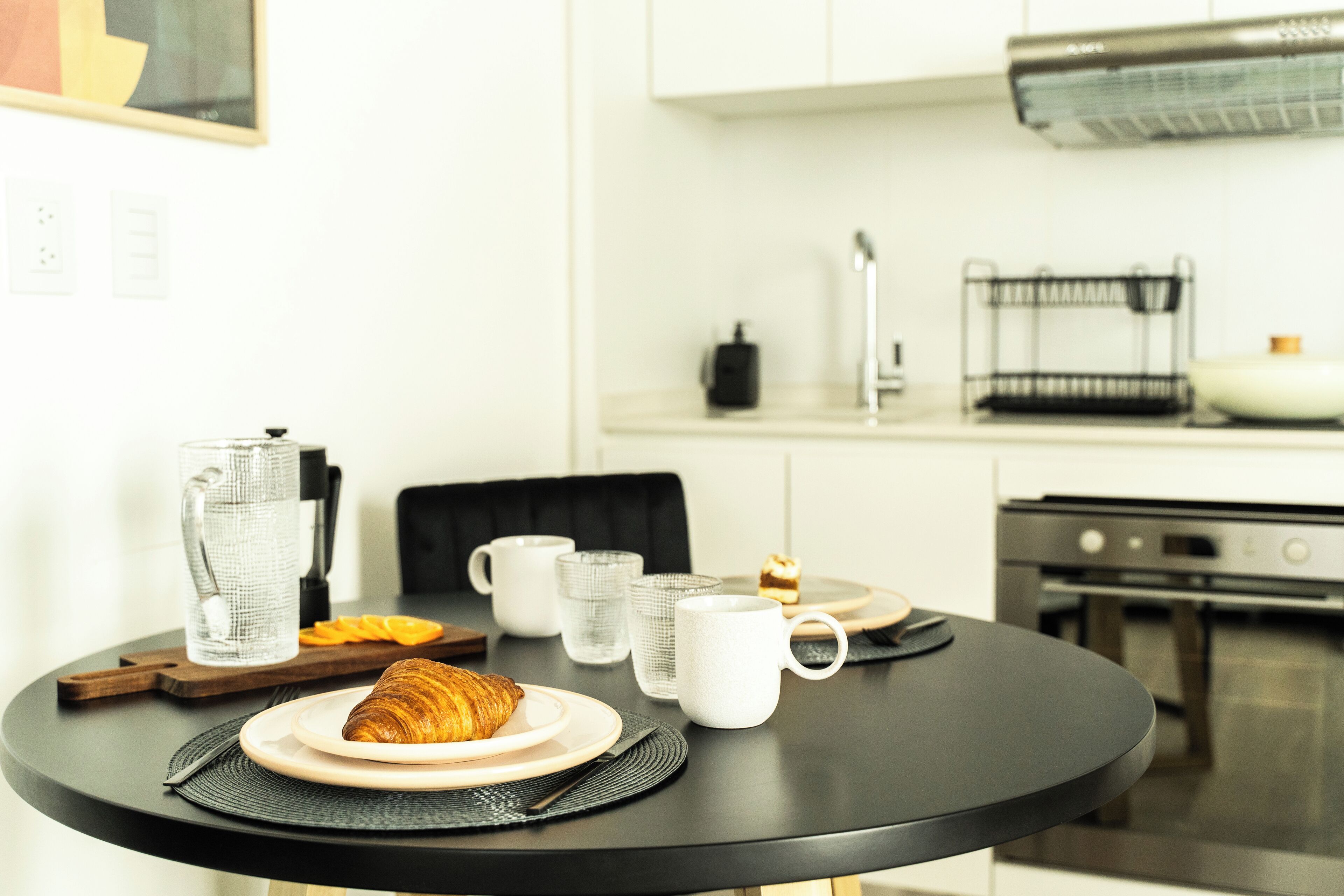 Une table de petit-déjeuner avec un croissant, du café et des tasses de thé.