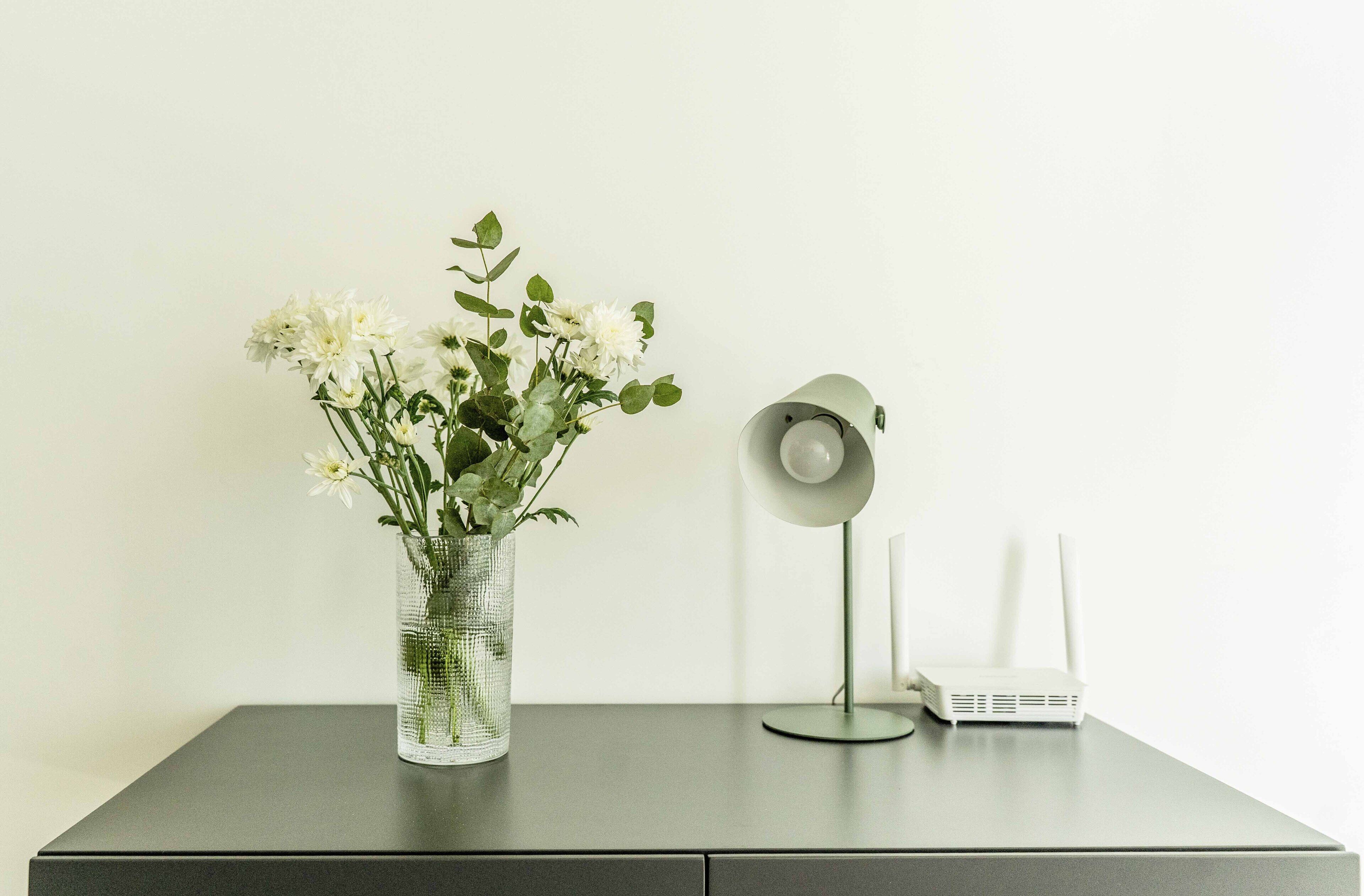 Uma mesa com um vaso de flores e um abajur.