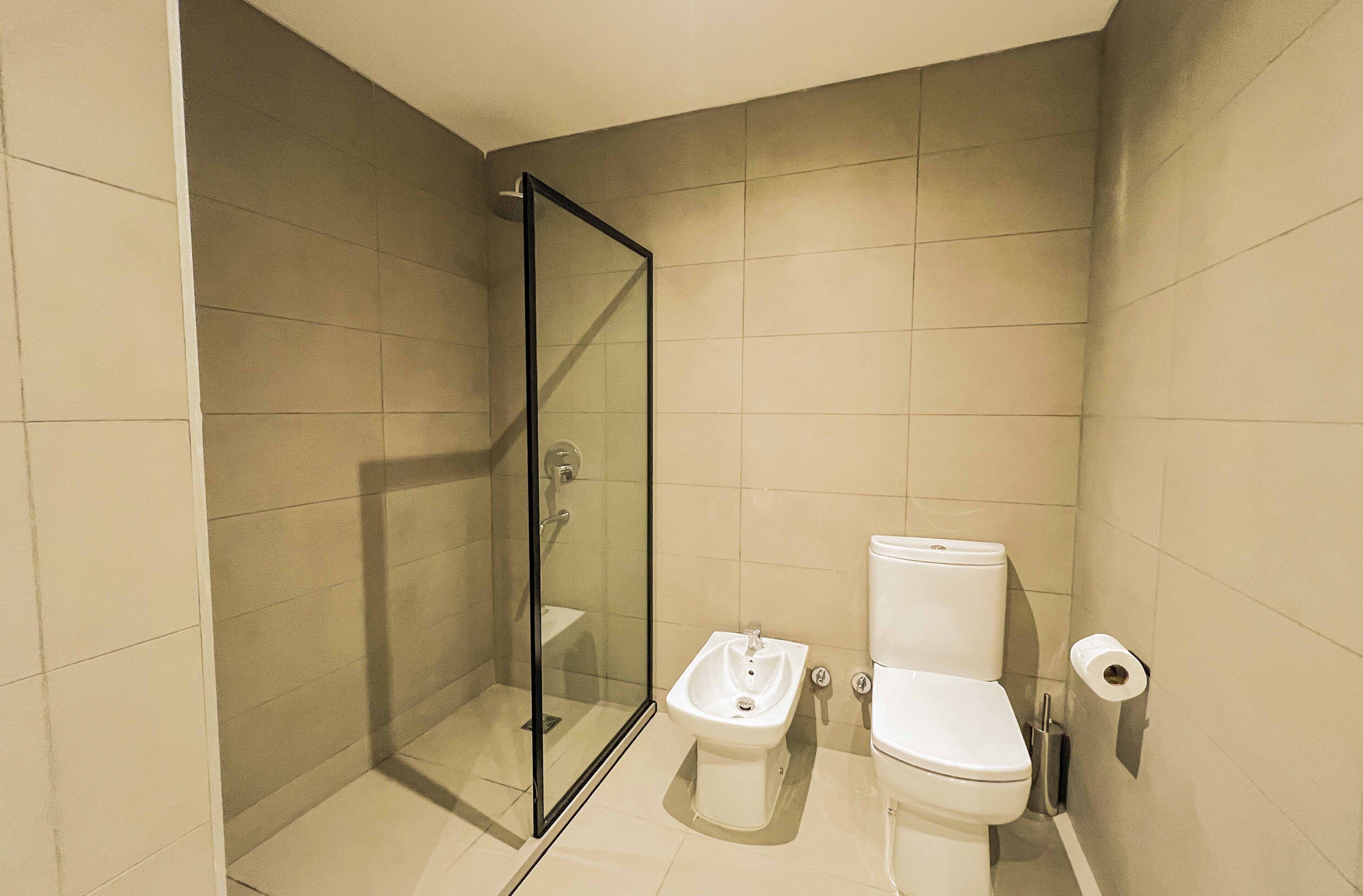 Un baño con ducha envuelta en vidrio, un bidé y un inodoro.