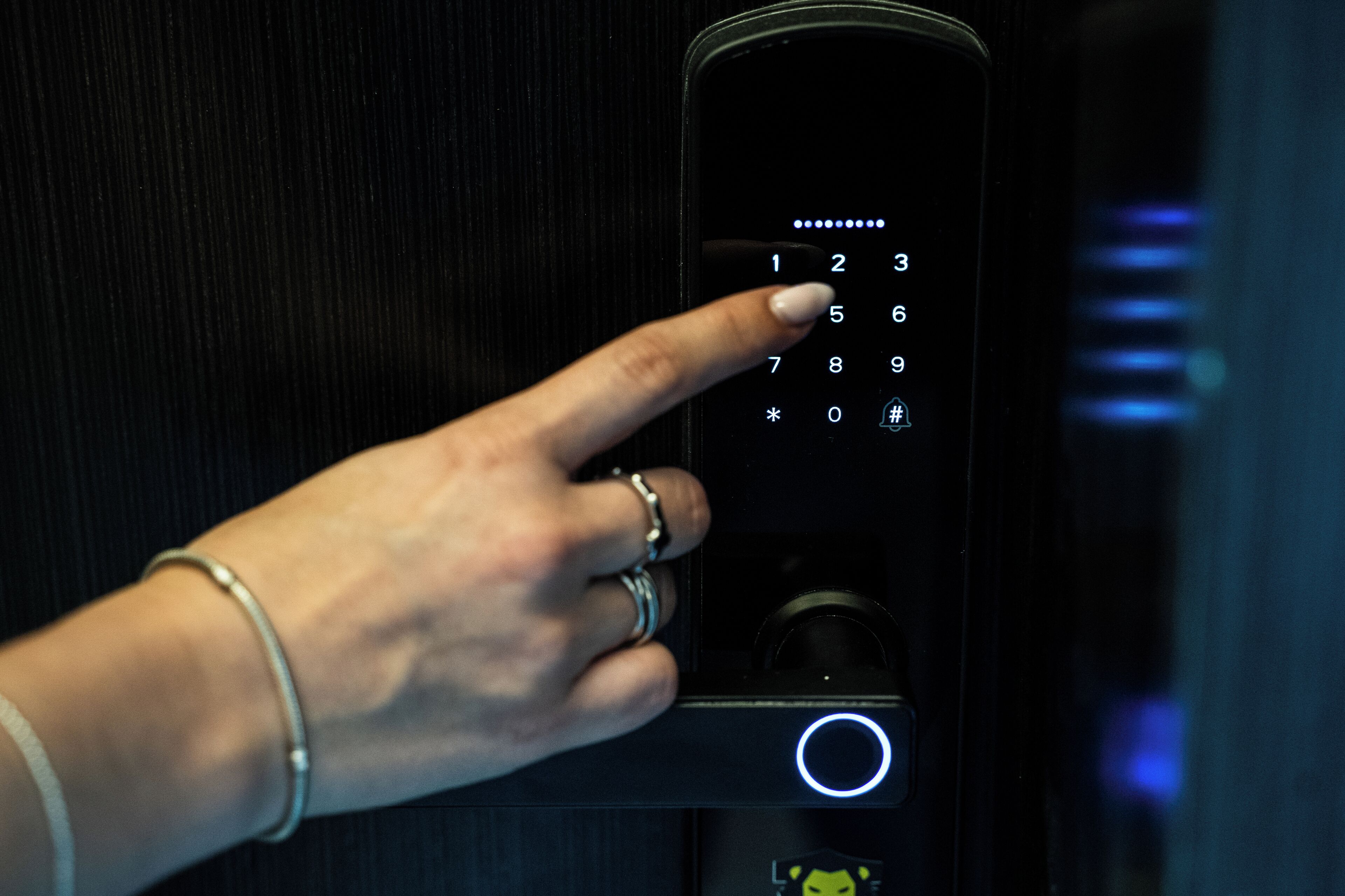 Een hand bedient een numeriek keypad op een modern paneel voor de liftbesturing.