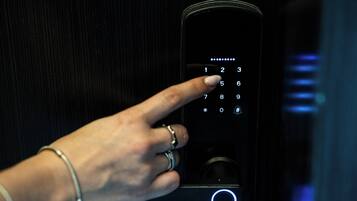 Een hand bedient een numeriek keypad op een modern paneel voor de liftbesturing.