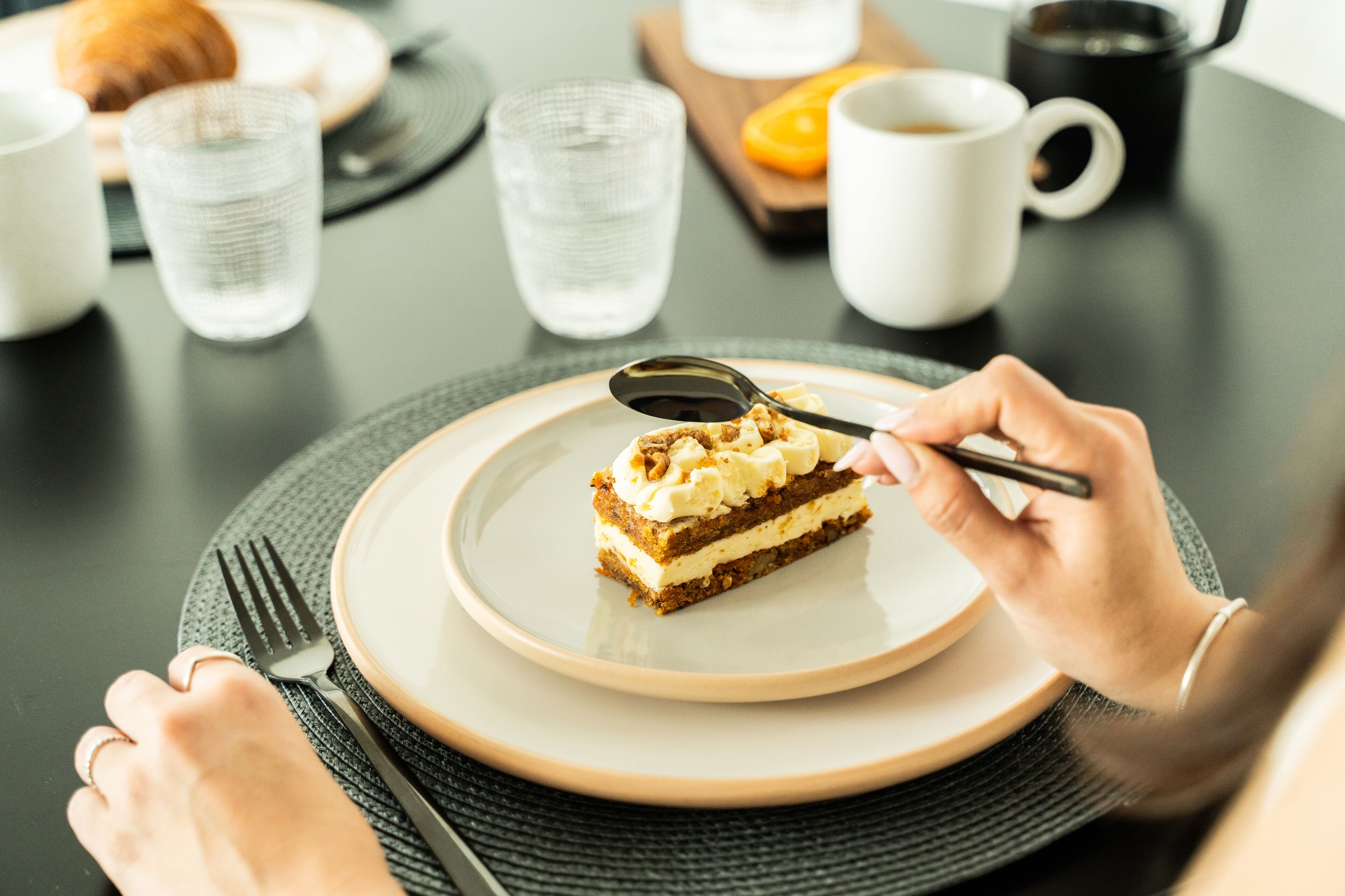Une table à manger avec une assiette de gâteau, une tasse de café et un verre d’eau.
