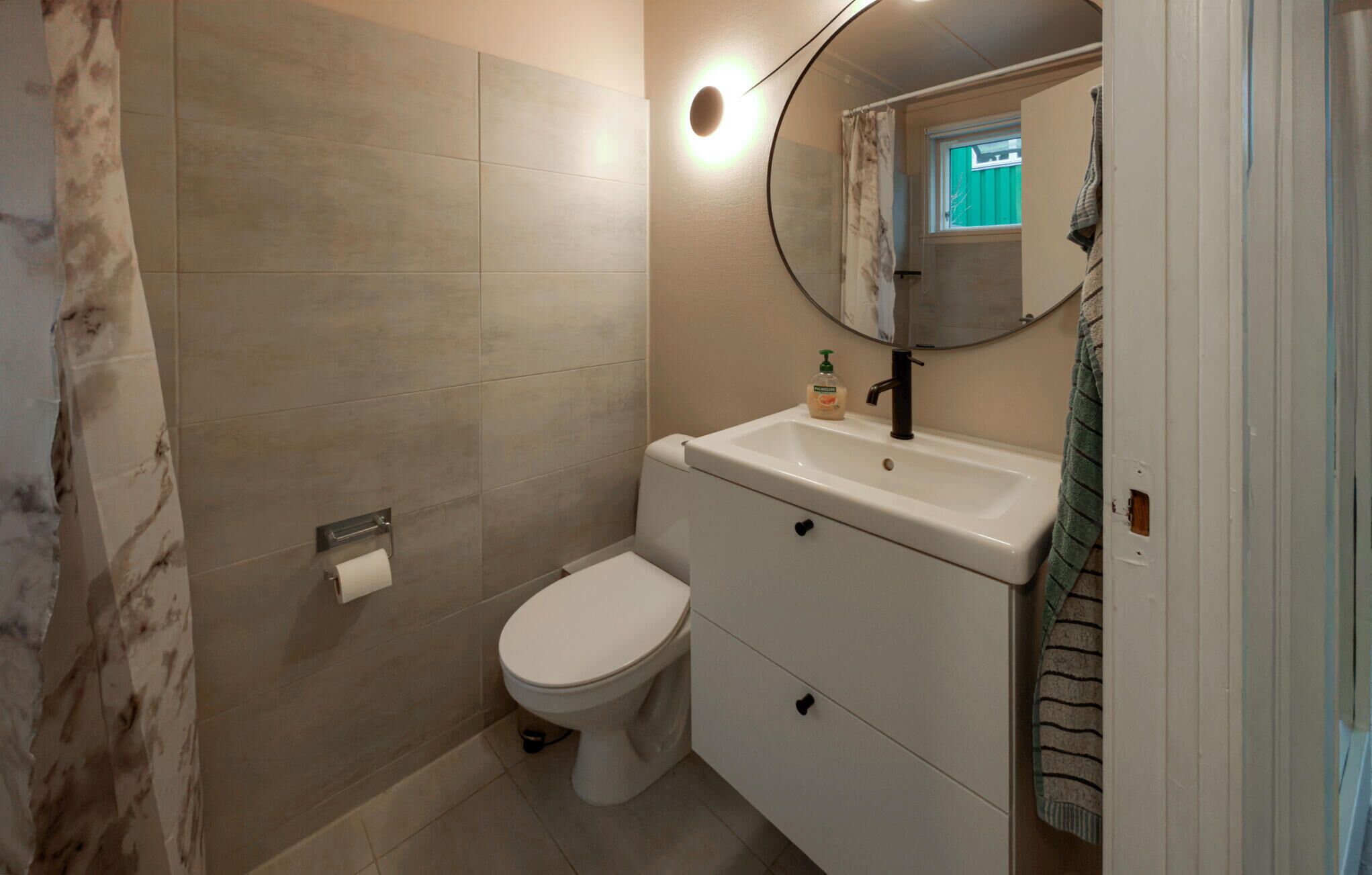 A bathroom with a toilet, sink, and mirror.